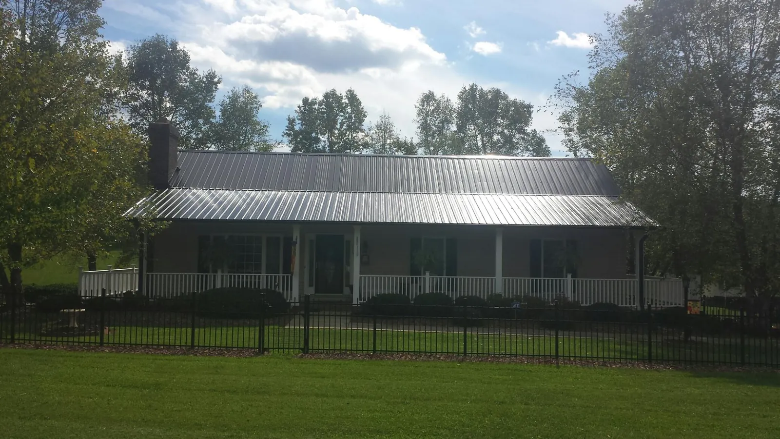 Gray metal roof on a brick ranch with a full width front porch — Gutter Guard Installation work by our crew in Litchfield